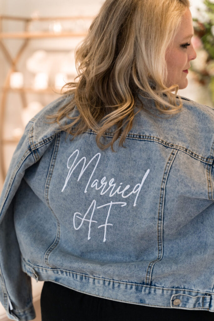 Bride in a white gown and denim jacket with 'Married Af' on the back.