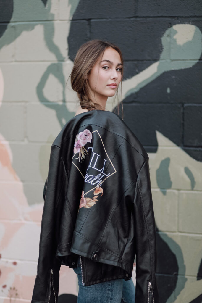 Young woman in a floral embroidered leather jacket with 'Till death' script.