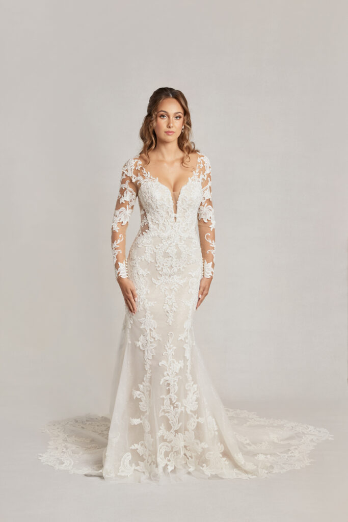 Model in a timeless winter wedding dress featuring intricate lace sleeves and a deep V-neck.