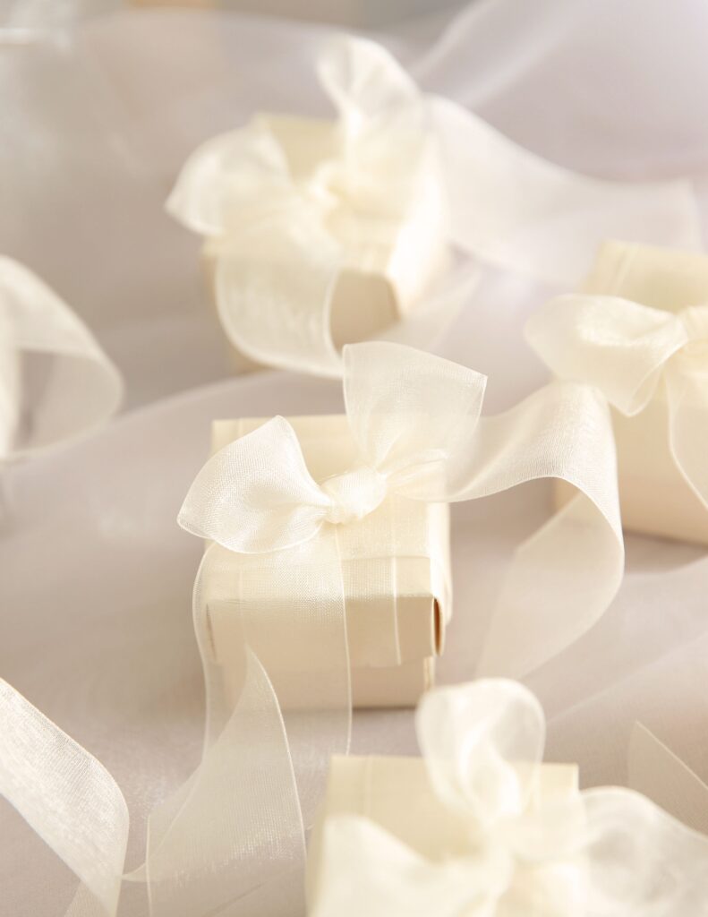 Close-up of elegant white wedding favors tied with silky ribbons.