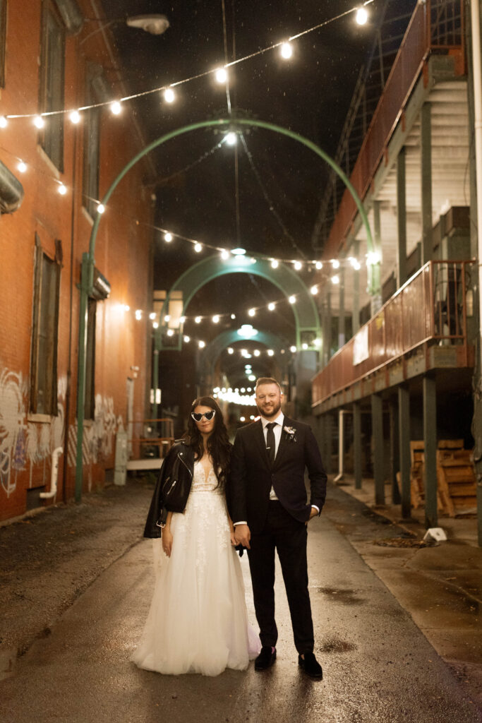 Bride and groom in urban night setting, bride in leather jacket.