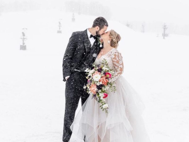 Snowy wedding scene with couple embracing, snowflakes gently falling around them.