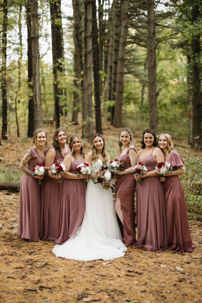 Bridal party in moody forest setting, bridesmaids in deep red dresses.