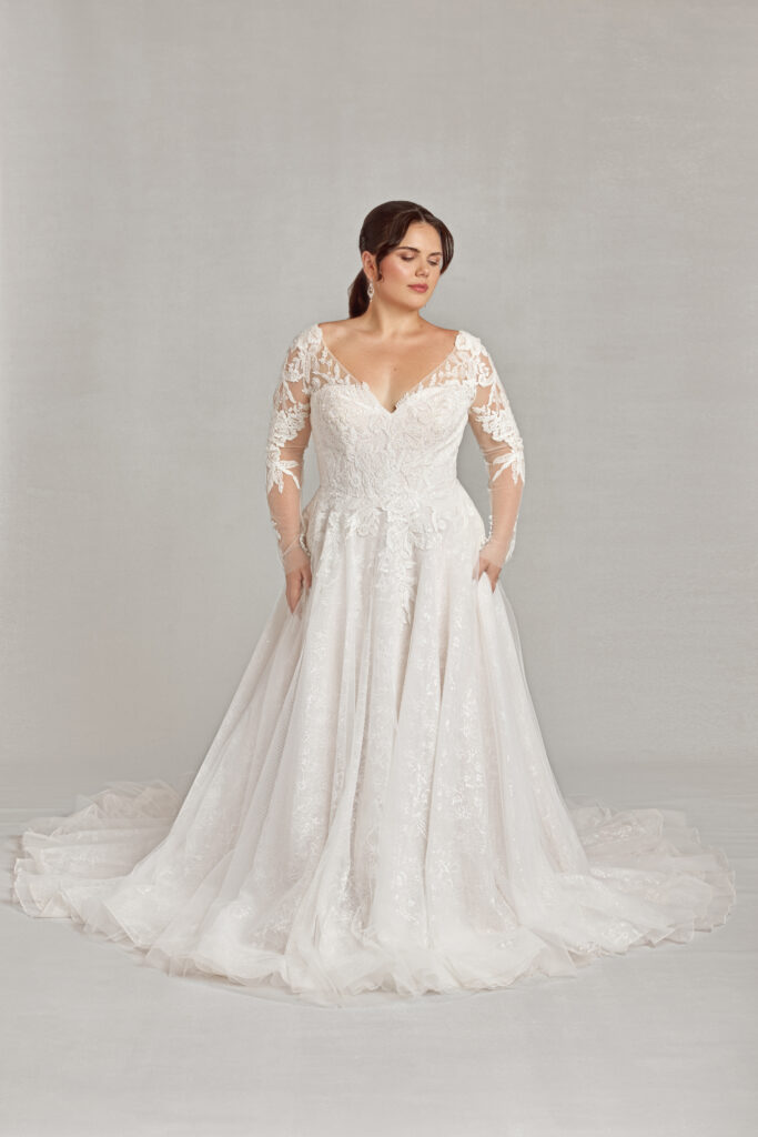 Bride in a detailed lace gown with three-quarter sleeves, looking off to the side.