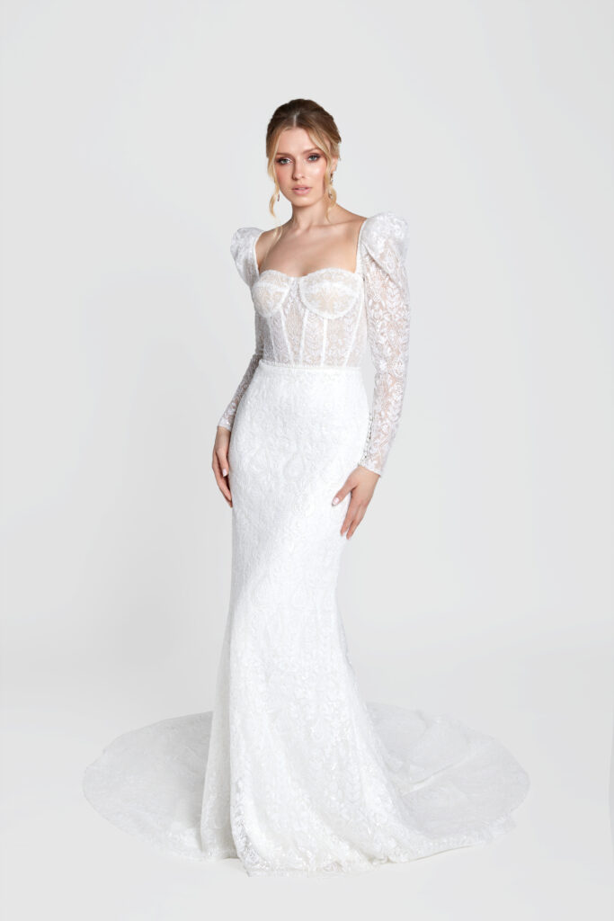 Graceful bride in a long sleeve lace gown with a dramatic train and puffy shoulders.