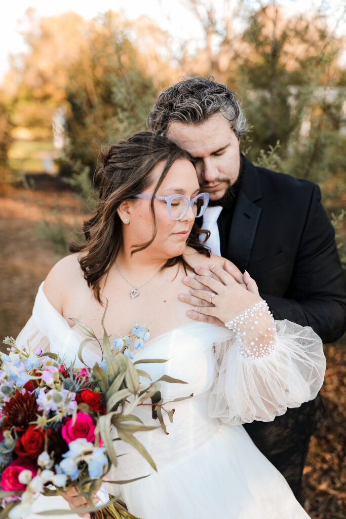 Intimate embrace of a couple in a forest setting, bride in a flowing dress with delicate details.