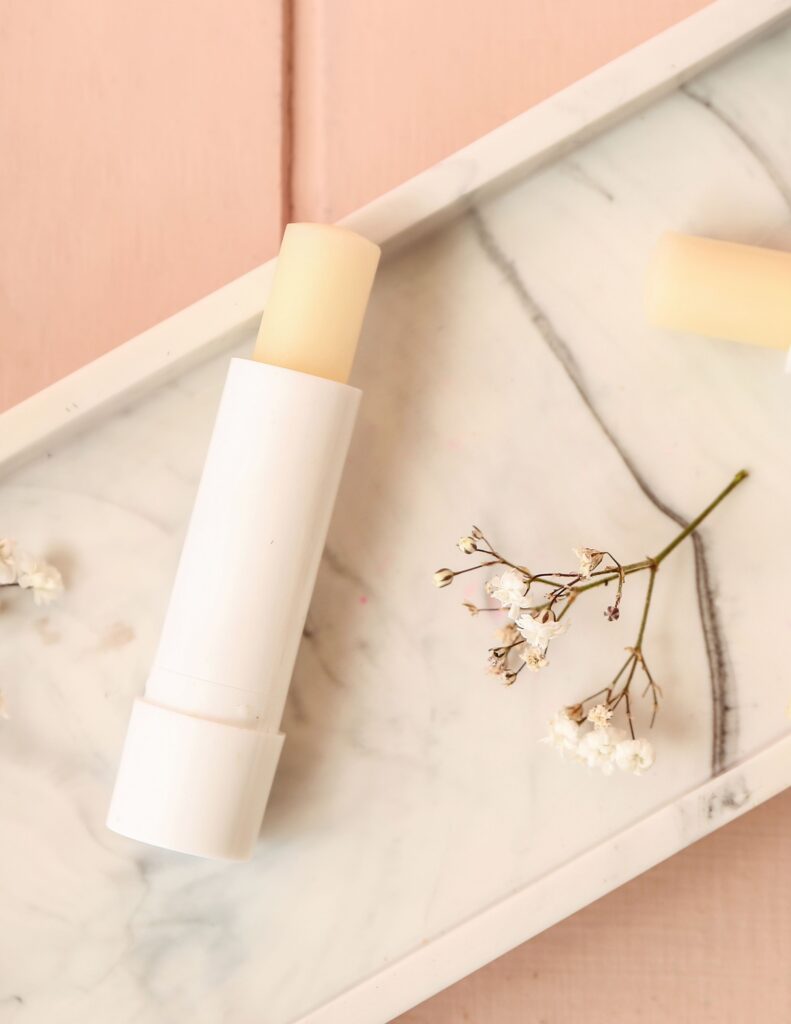 Simple lip balm on a marble tray with delicate dried flowers.