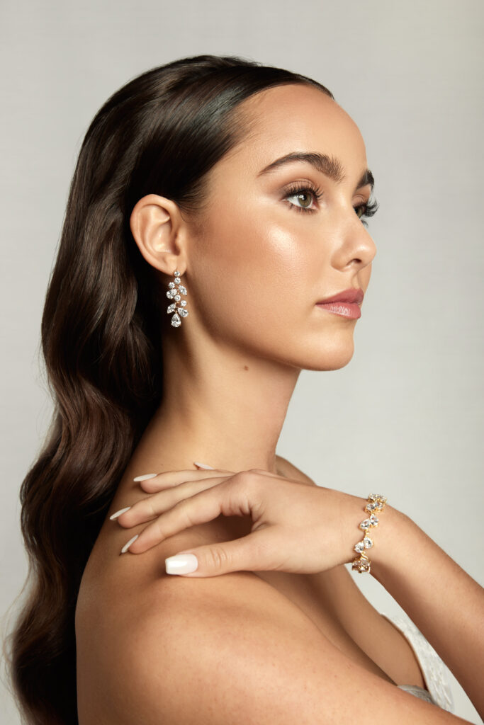 Model displaying a side profile wearing drop diamond earrings and a matching bracelet, emphasizing classic bridal elegance.