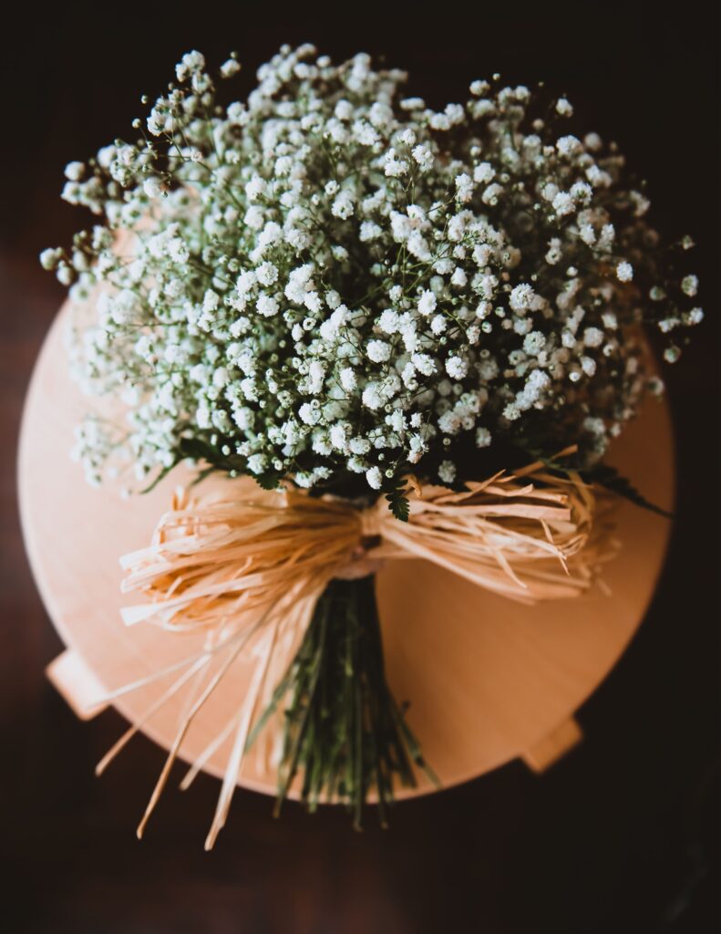 Bouquet of baby's breath flowers tied with rustic raffia, placed on a light wooden surface for a minimalist look.