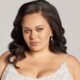 Plus-size bride with voluminous waves and natural glam makeup, wearing a lace bridal gown with intricate beaded details.