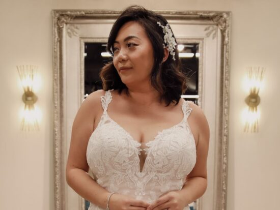 Close-up of a bride in a lace wedding gown featuring intricate floral patterns and a deep neckline, paired with a soft, glamorous hairstyle.