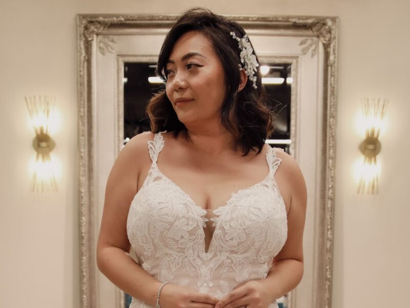 Close-up of a bride in a lace wedding gown featuring intricate floral patterns and a deep neckline, paired with a soft, glamorous hairstyle.