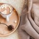A wooden tray featuring hot cocoa with marshmallows, pinecones, and a candle, evoking warmth and charm for a winter reception.