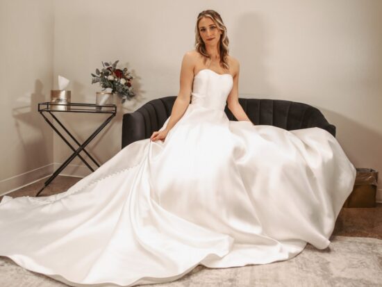 Full-skirt mikado wedding dress with a strapless neckline, seated bride exuding timeless bridal sophistication in a chic setting.