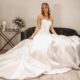 Full-skirt mikado wedding dress with a strapless neckline, seated bride exuding timeless bridal sophistication in a chic setting.