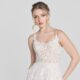 A model wears a romantic A-line wedding dress with a sheer, lace-adorned bodice and delicate spaghetti straps.