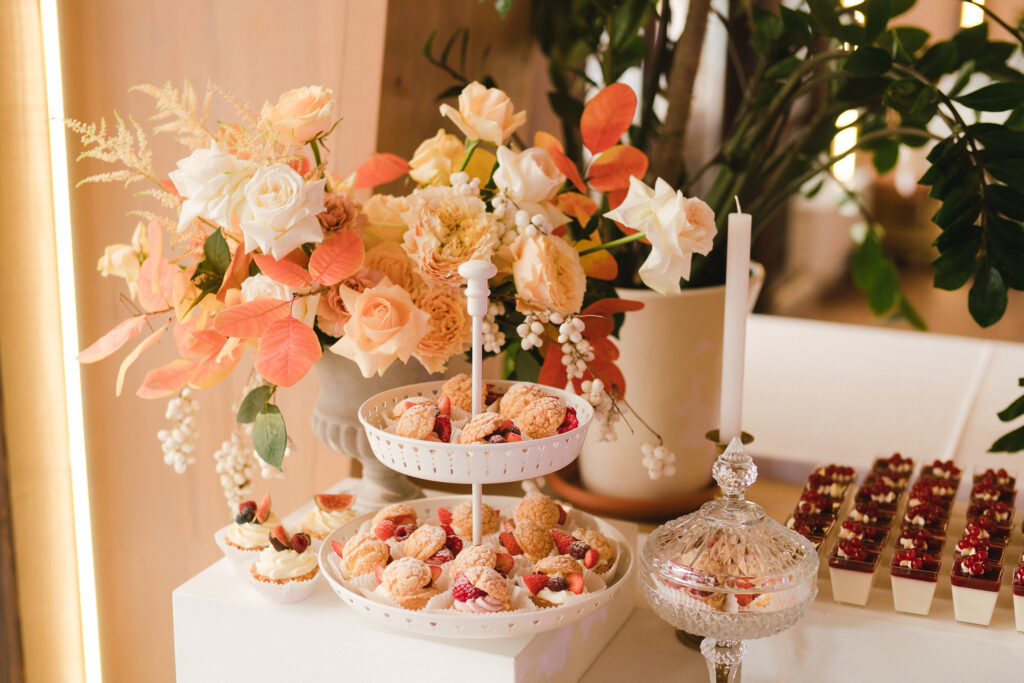 Charming dessert display featuring a white cupcake tower with fresh berries, floral accents, and a variety of mini berry parfaits.