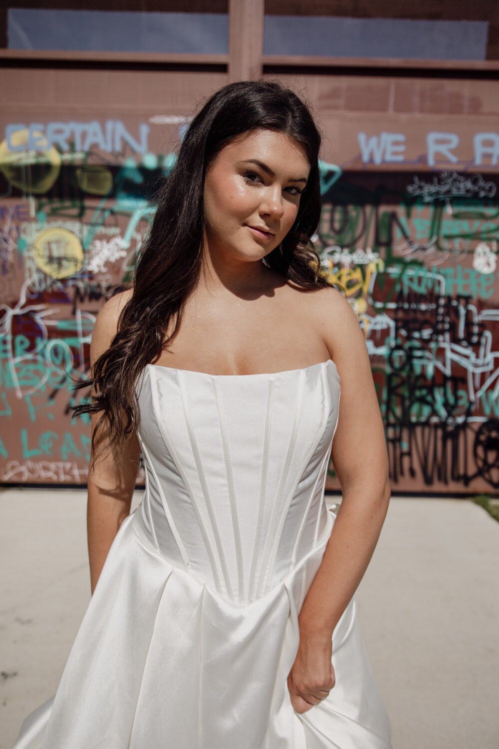 A close-up of a bride wearing a strapless corset wedding gown, showing the pleated detail and structured lines of the bodice.