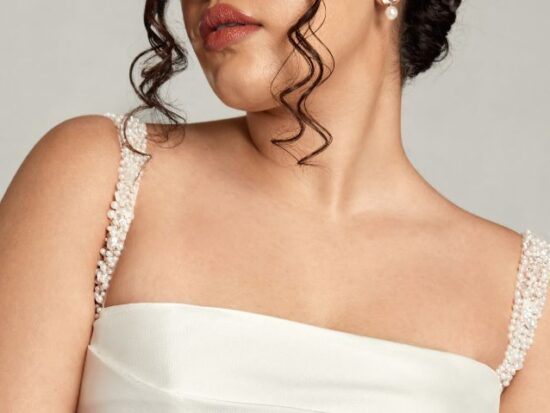 The image highlights the bride’s beaded straps and soft curls, framing her shoulders and the top of her structured square neckline wedding dress.