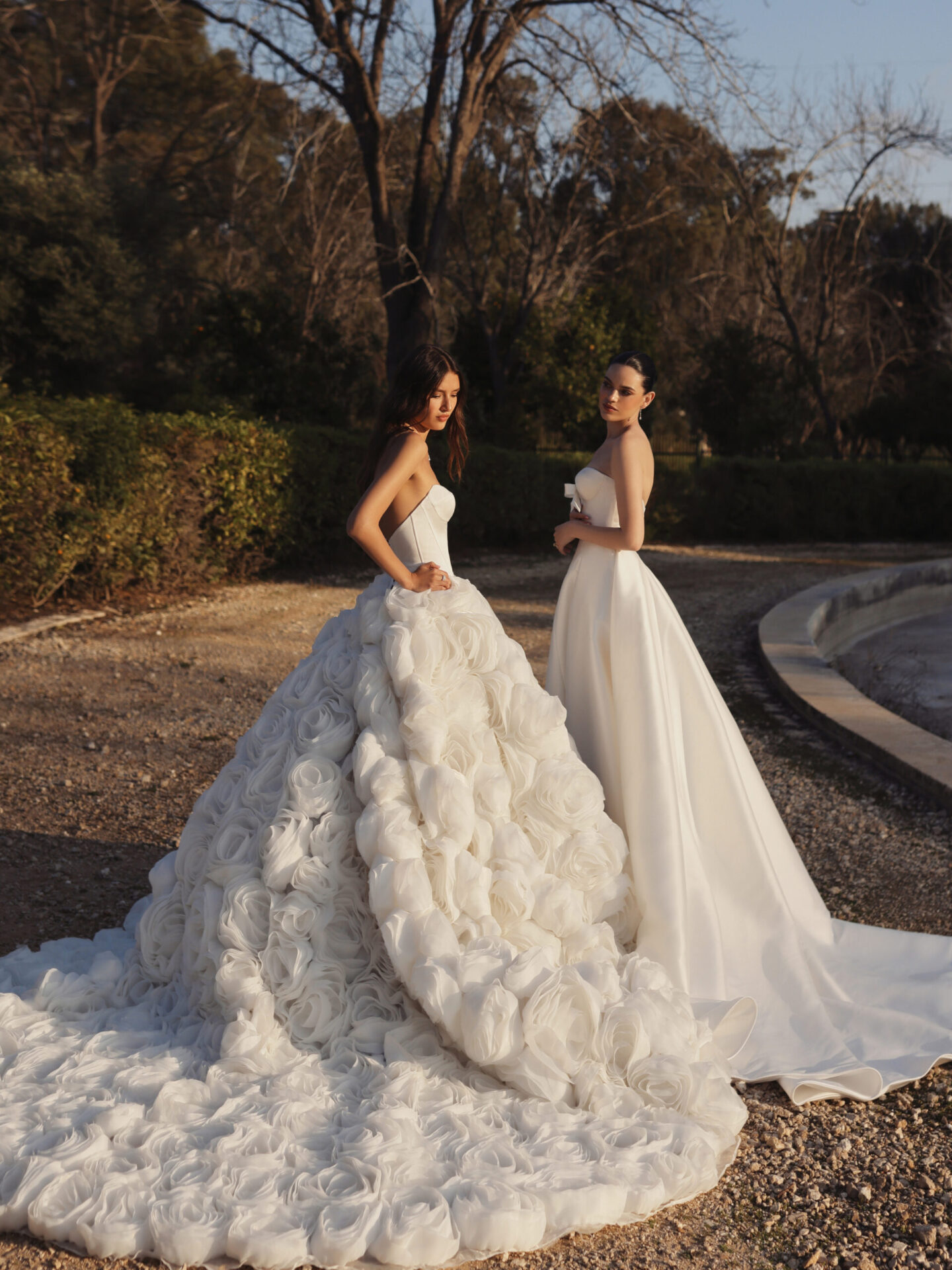 two women wearing different style bridal dresses outside