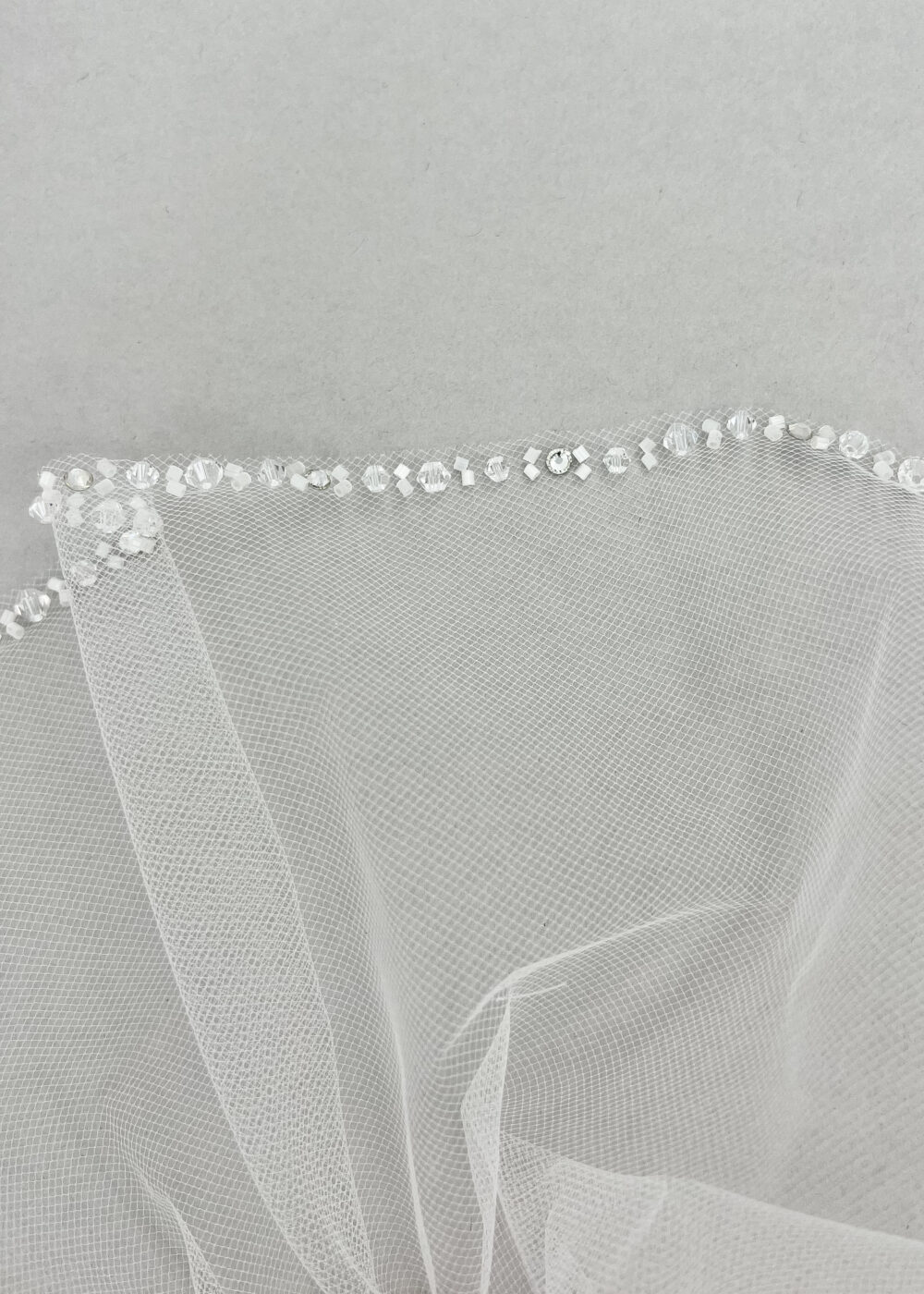 Close-up on the end of a wedding veil with small silver jewels attached to the veil.
