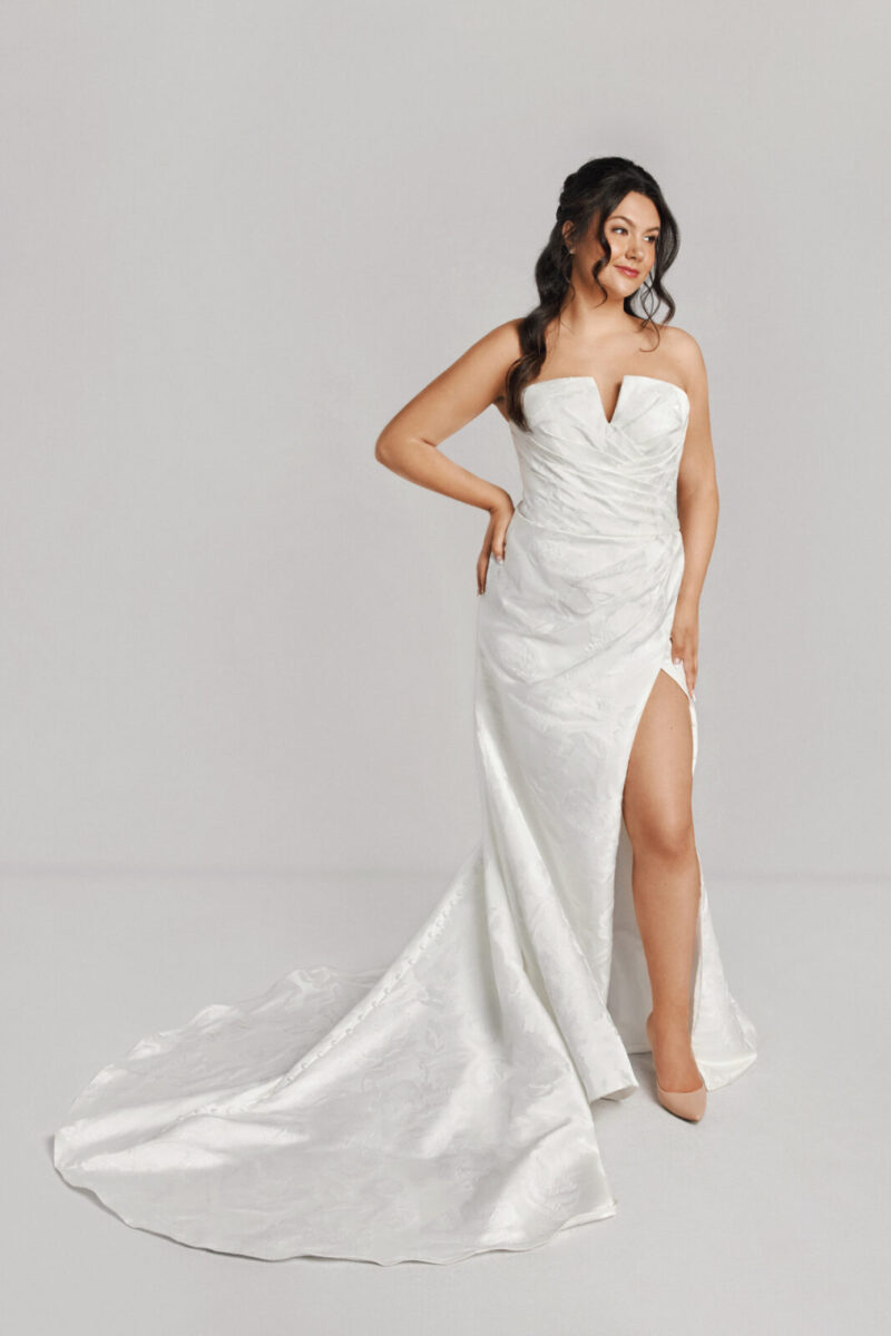 A bride in a white fitted slim strapless dress with a bow on the back.