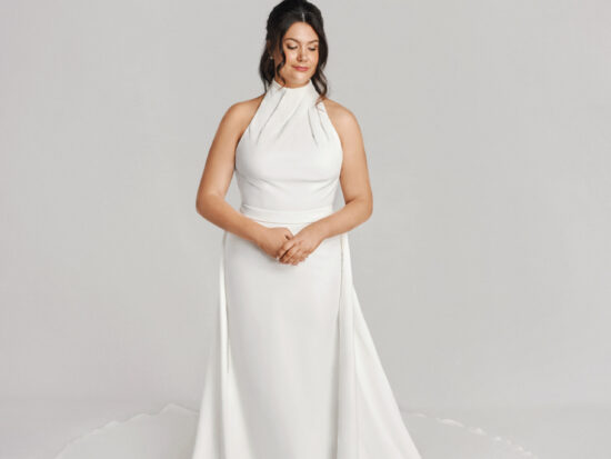 A bride in a white flowy floor length sleeveless dress.