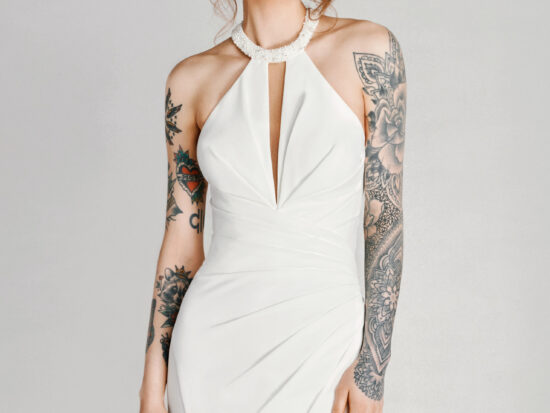 A bride with tattoos in a white flowy dress with leg slit.