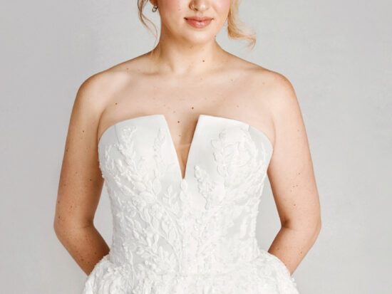 A bride in a white fitted deep v cut strapless floral lace dress.