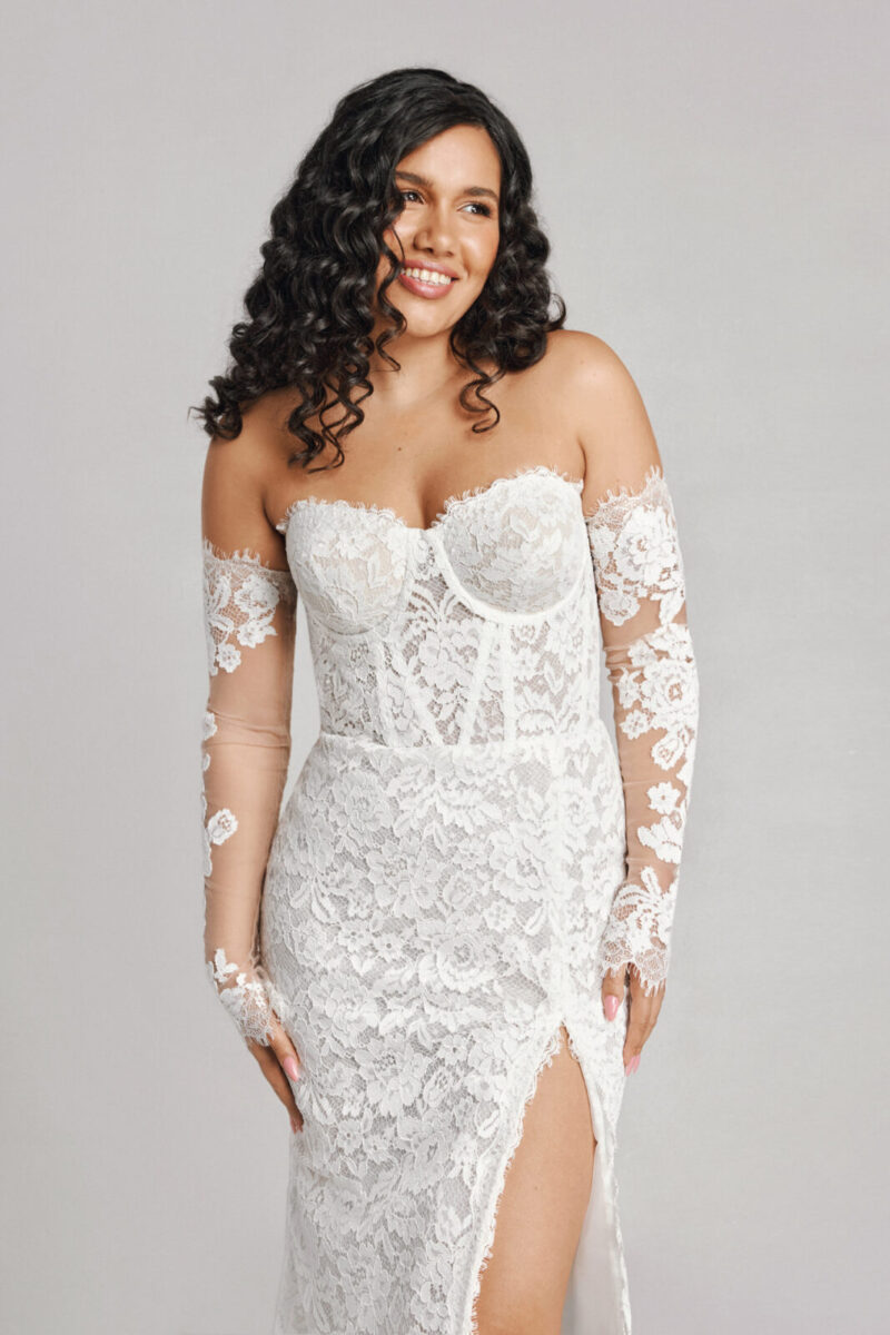 A bride in a white flowy sheer long sleeve floral open back dress.