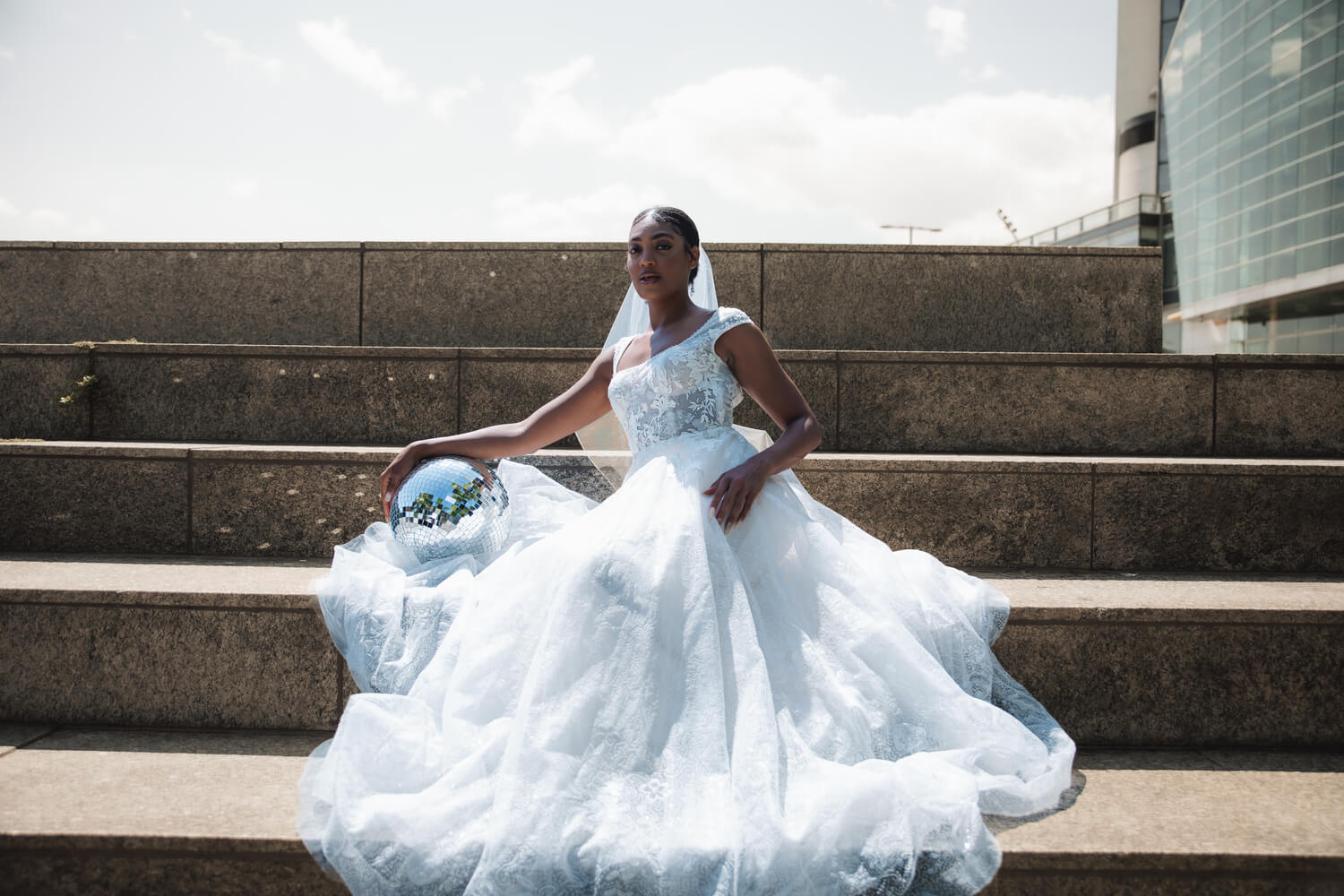 The Wedding Shoppe bride lounging on wide concrete steps.