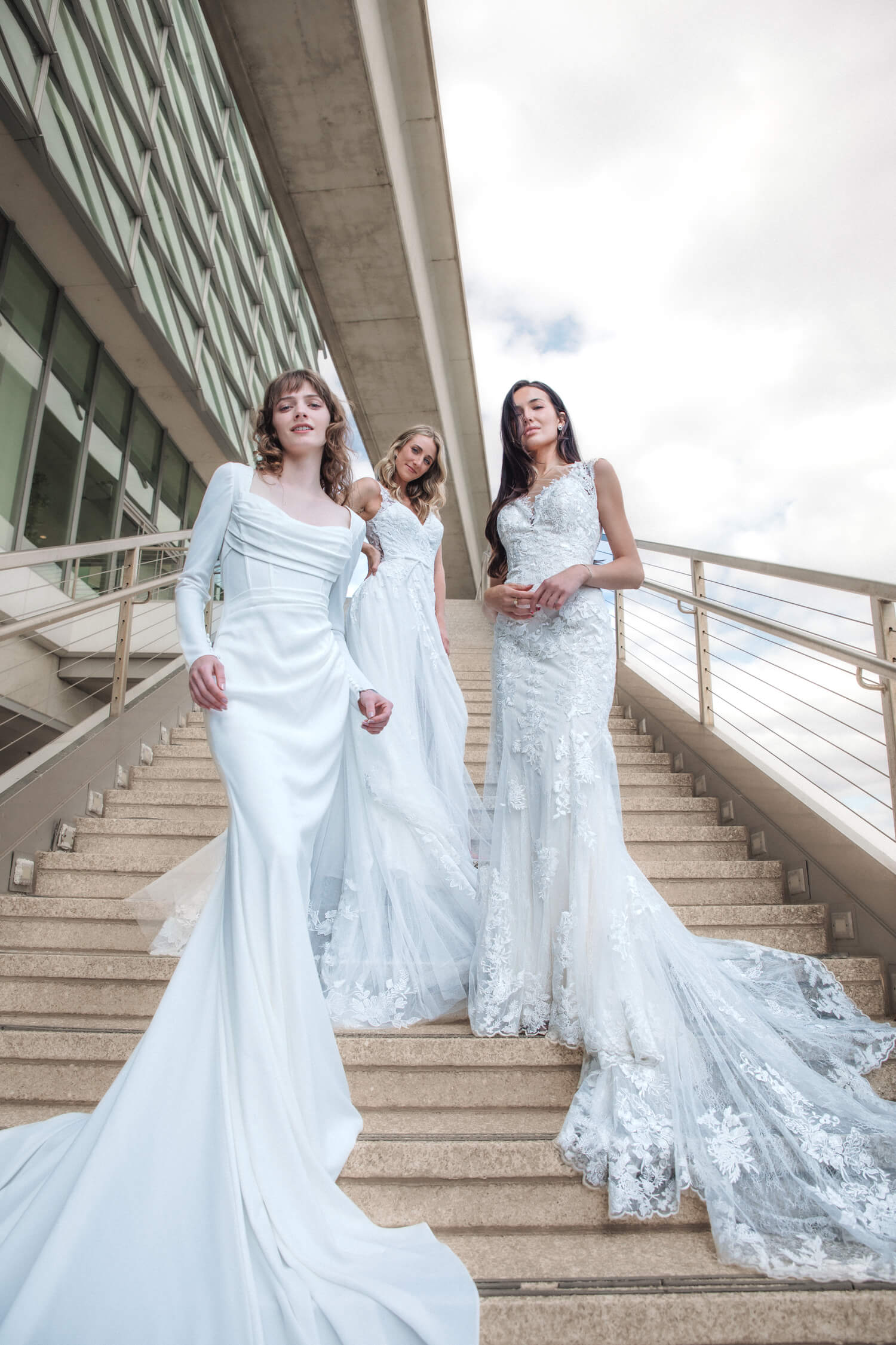 Three The Wedding shoppe bridal models standing on the steps of a building.