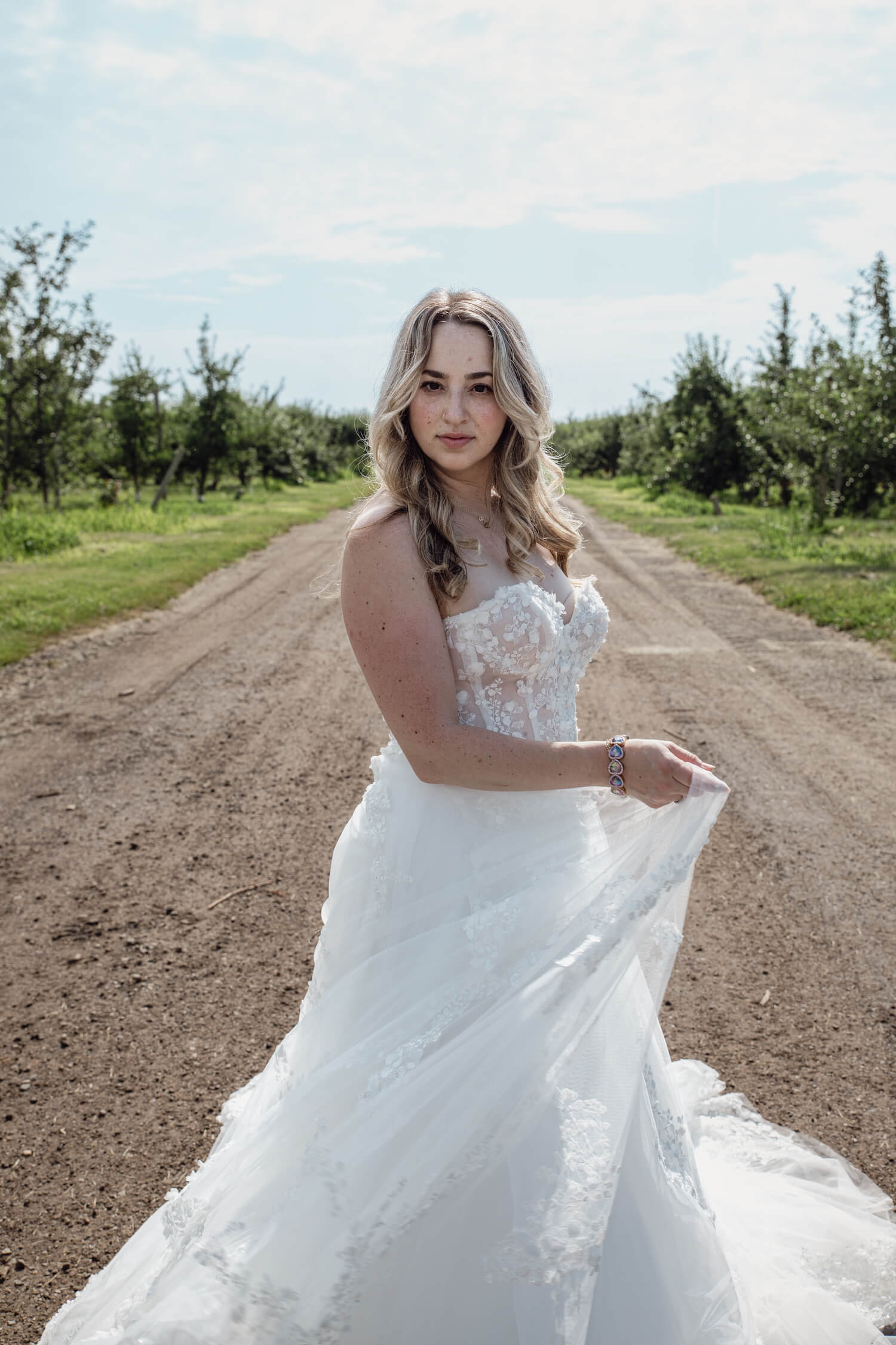 Bride to be twirling her wedding dress on a dirt road.