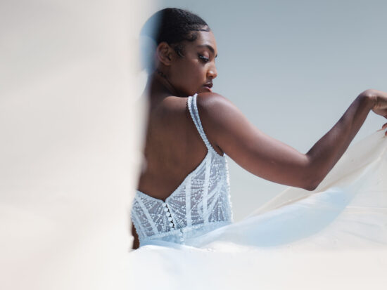 A bride in a delicate white gown looks over her shoulder as she twirls, framed by soft lighting and a dreamy backdrop.