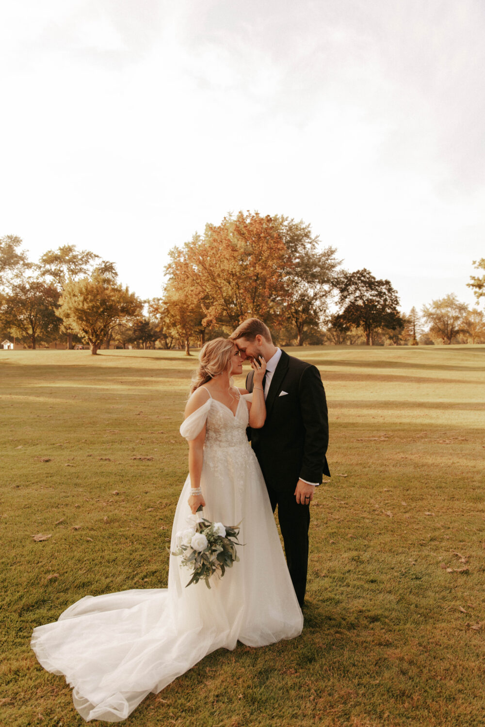Bride and groom holding hands in an open field during golden hour.