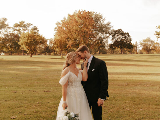 Bride and groom holding hands in an open field during golden hour.