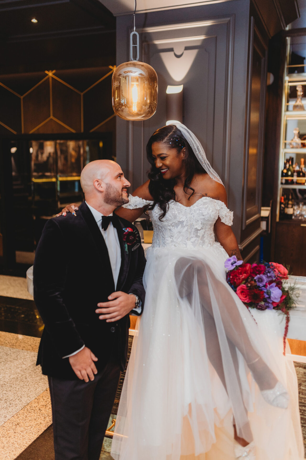 Bride and groom celebrating indoors, bride popping champagne in a modern venue.