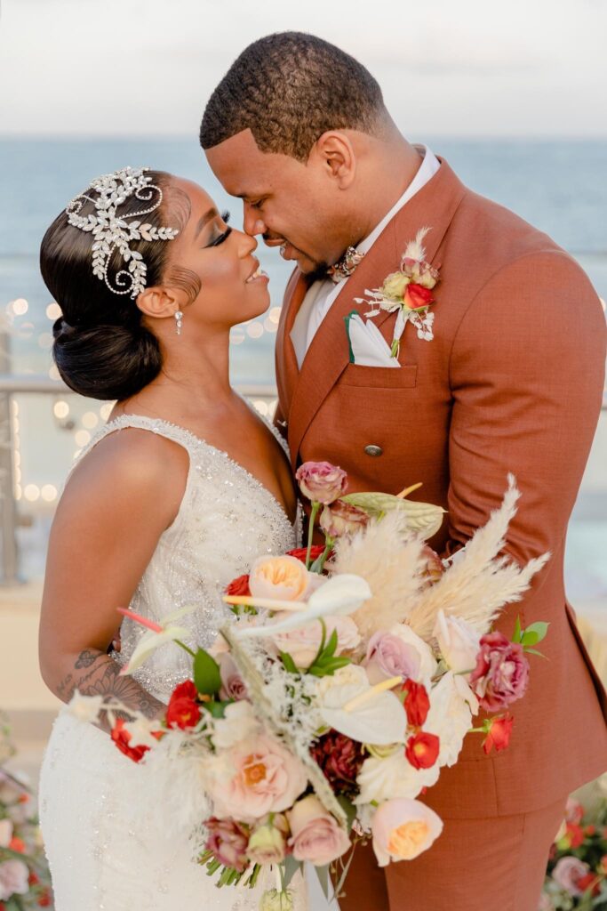 Bride and groom embracing and smiling with peach and white bouquet.