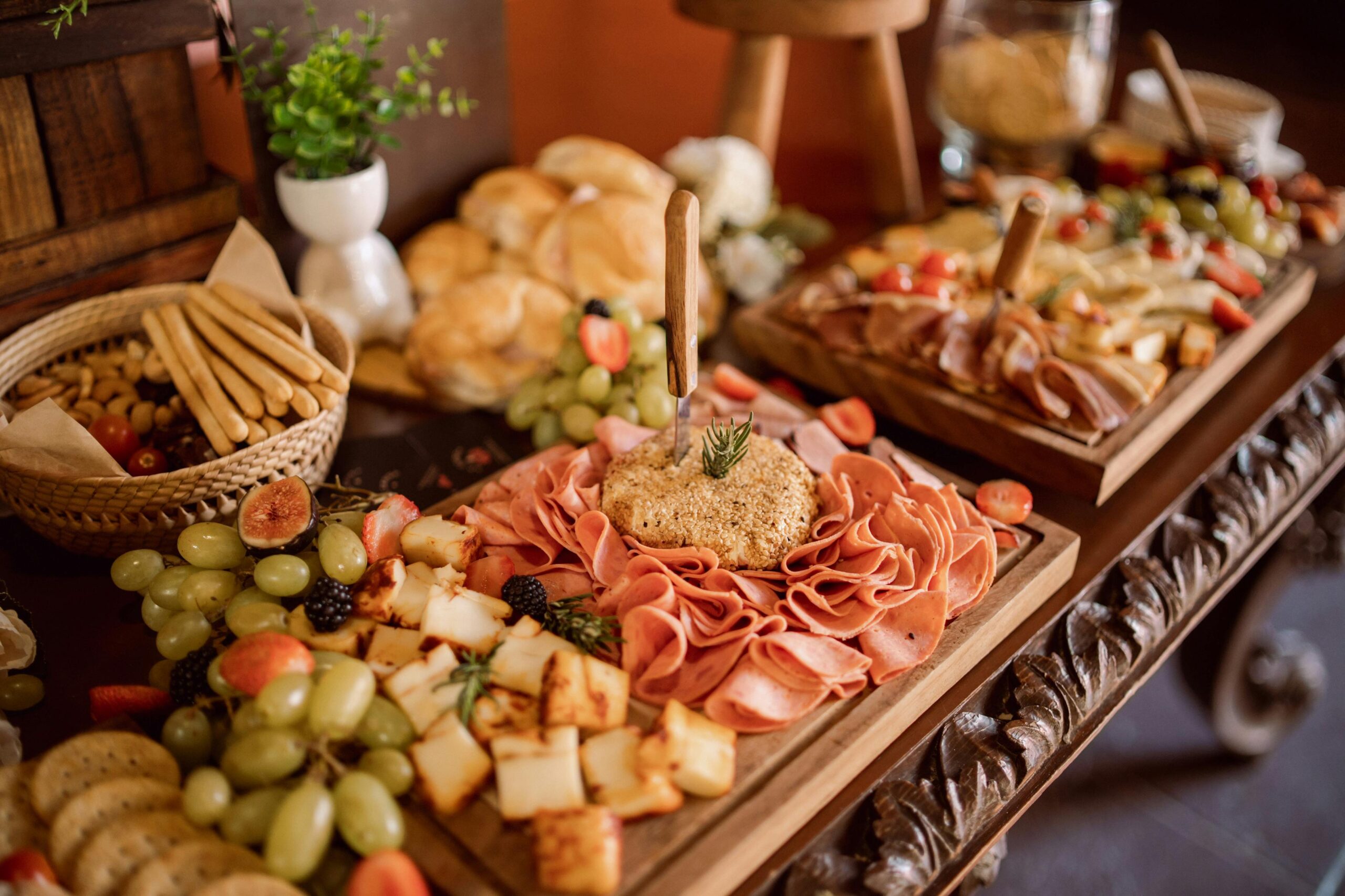 A charcuterie-style wedding food table featuring assorted meats, cheeses, breads, and fresh fruit.