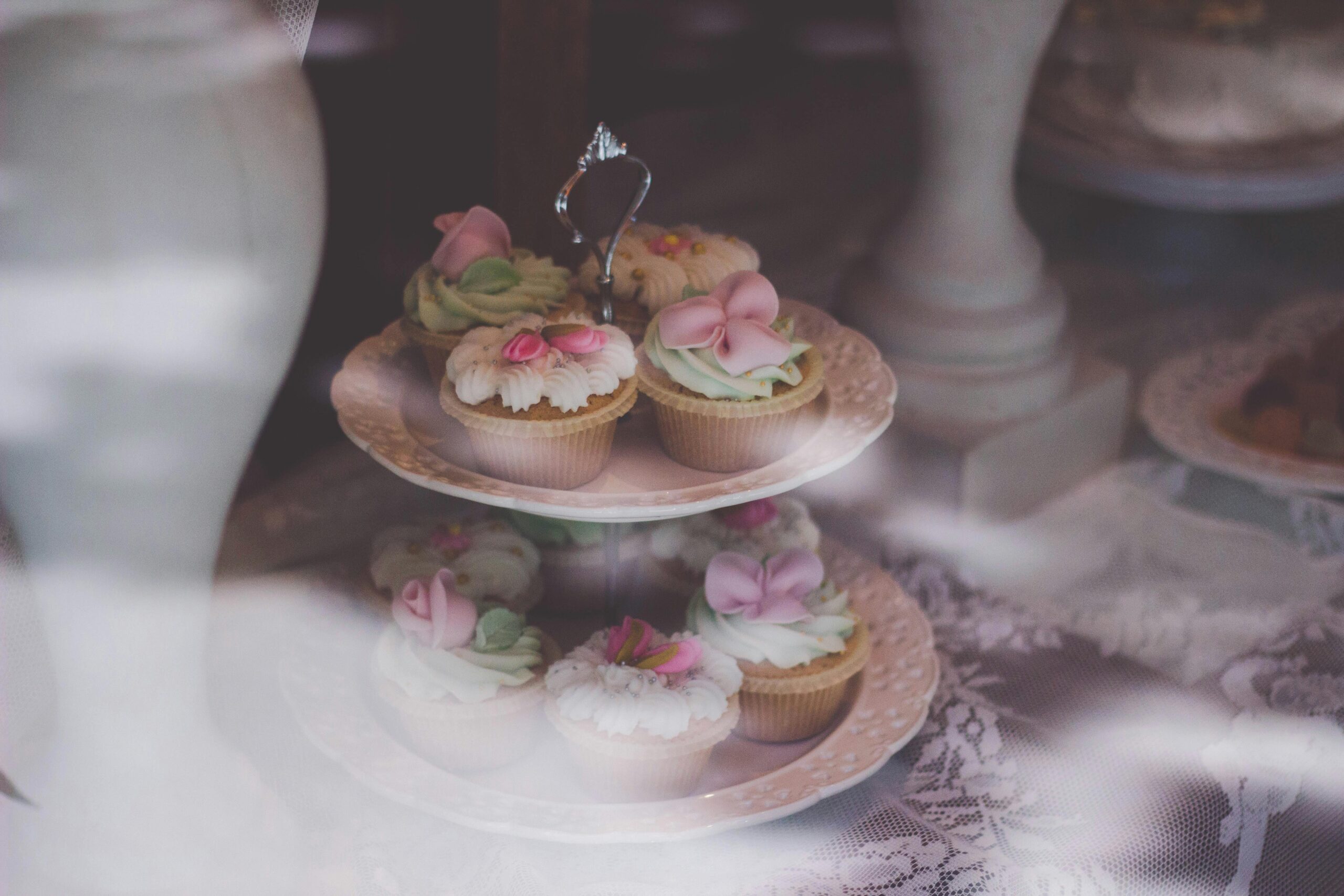 A tiered display of elegant mini desserts decorated with pastel flowers at a spring wedding reception.