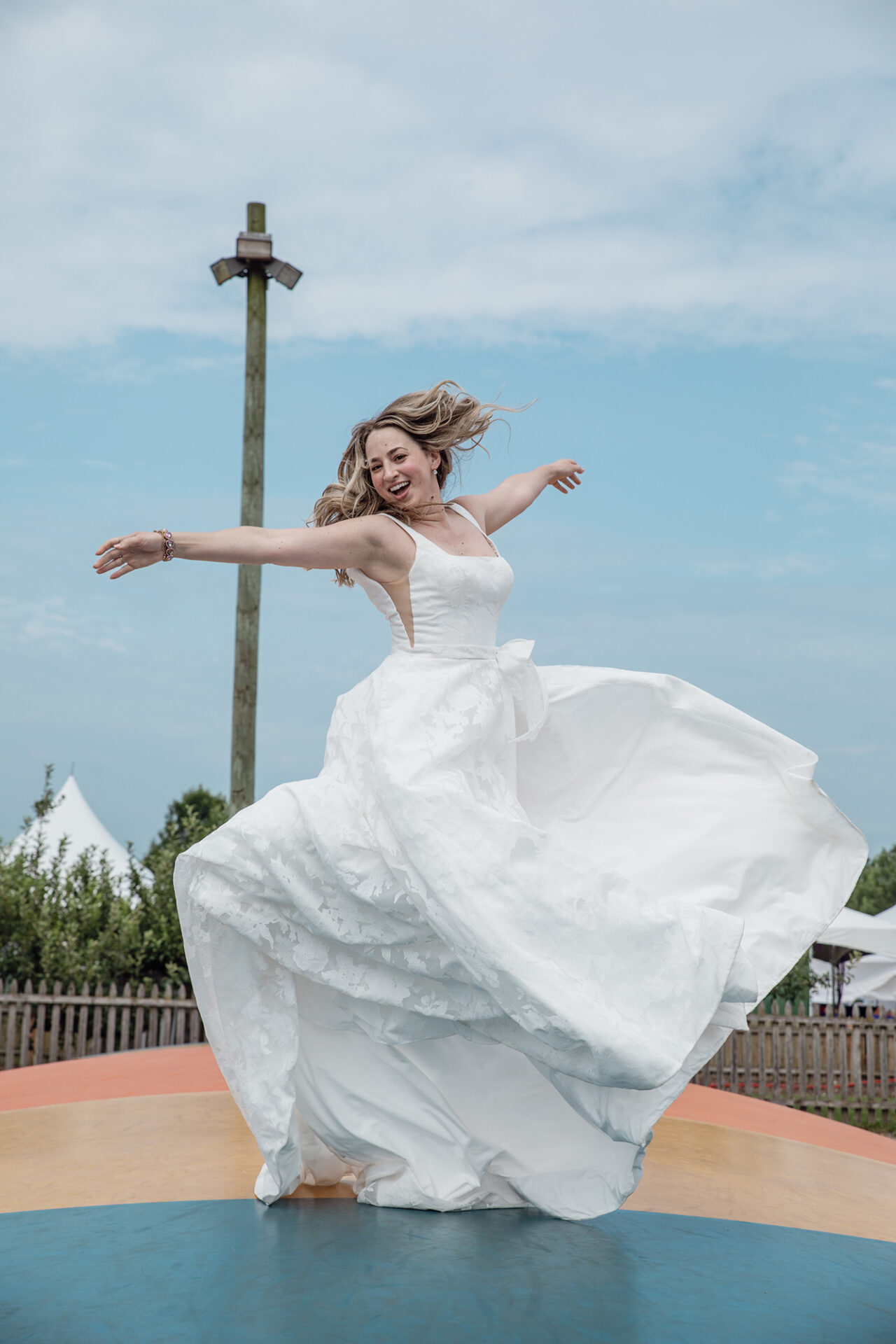 Bride twirling in a flowy gown near a columned terrace or monument.