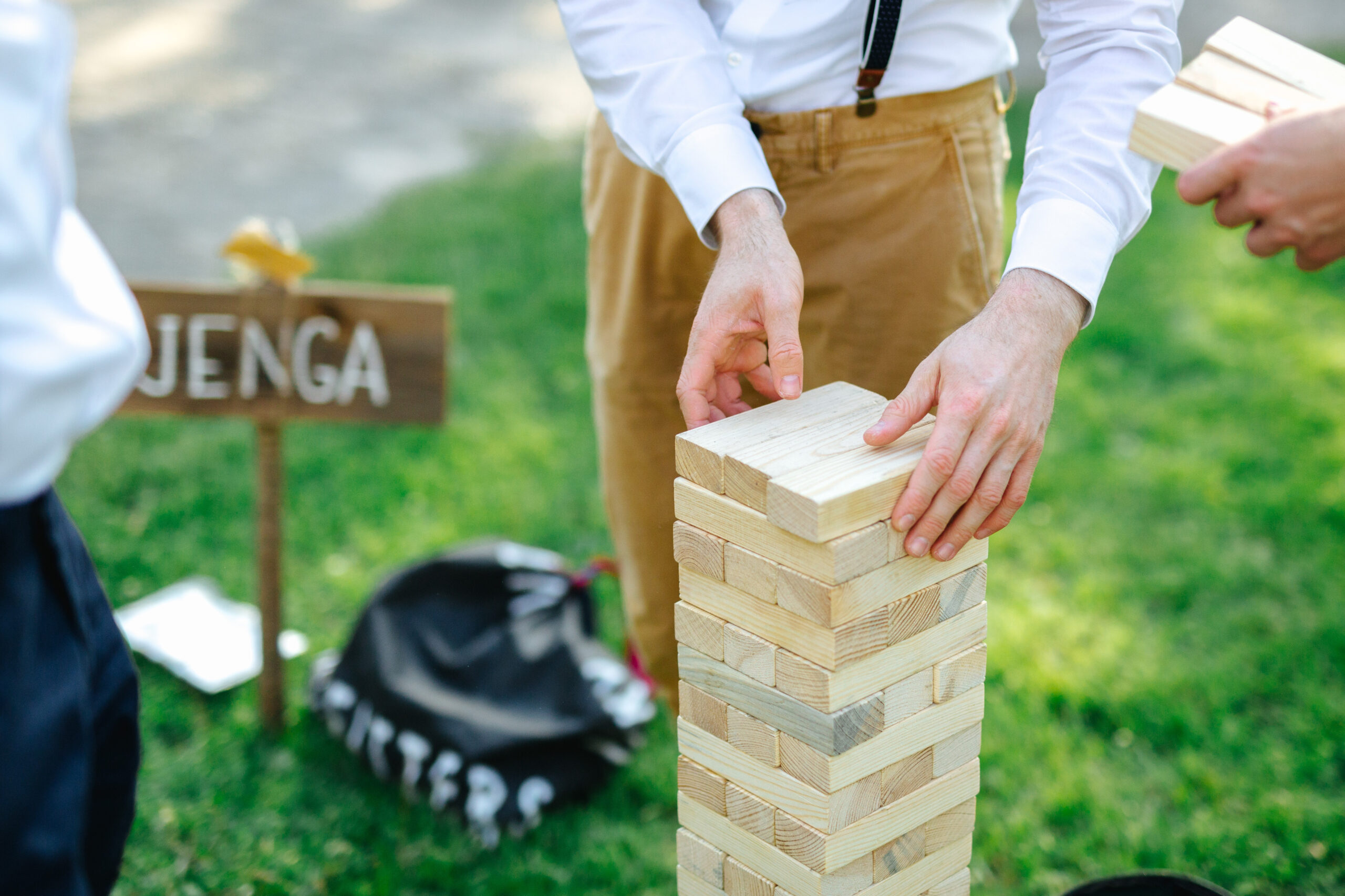 Guests playing a large wooden Jenga game during an outdoor wedding.