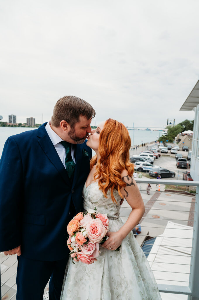 Bride with red hair and groom in navy suit sharing a close moment while holding a pink bouquet.