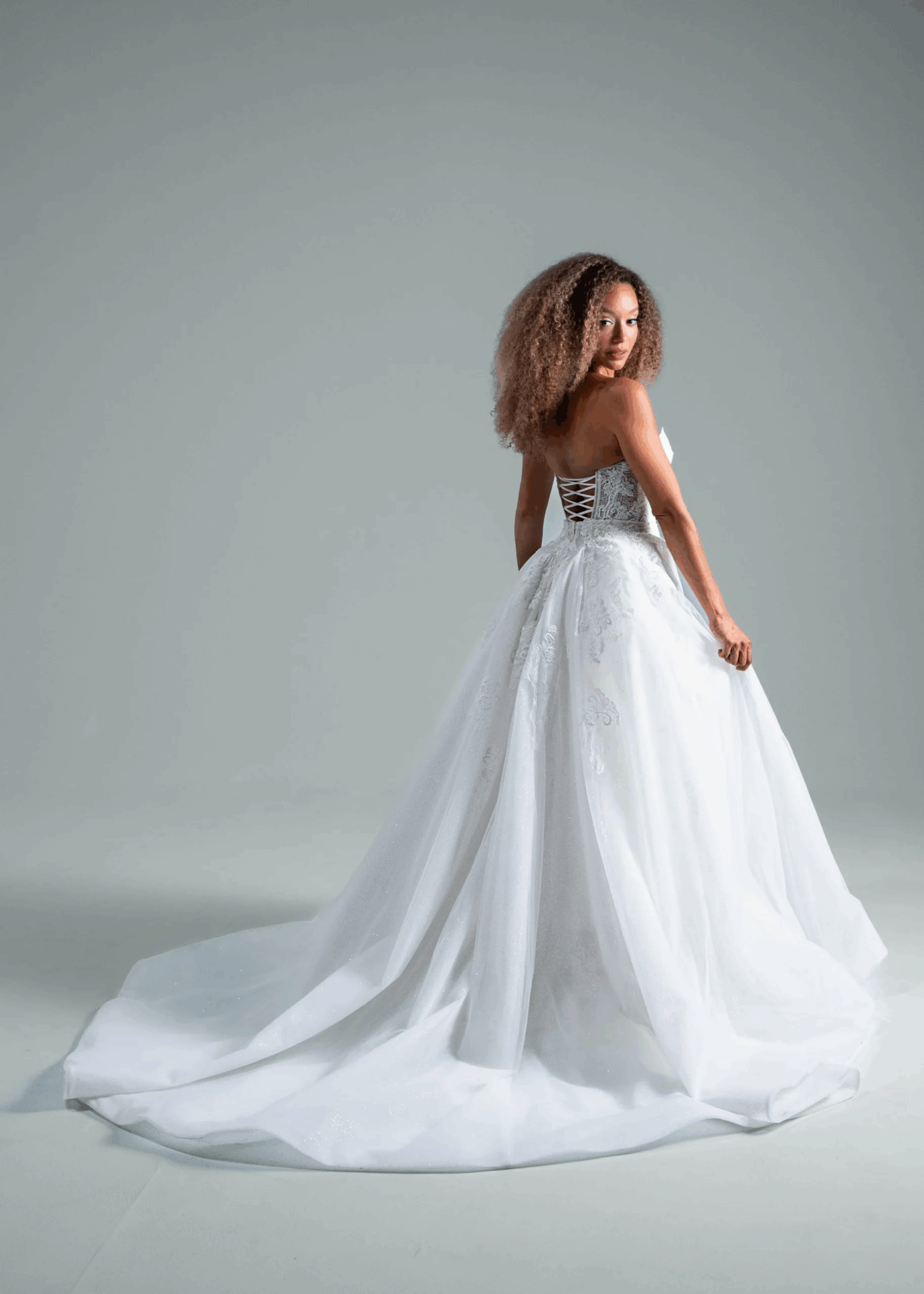 Bride in a strapless white wedding dress posing to highlight the long, elegant train.