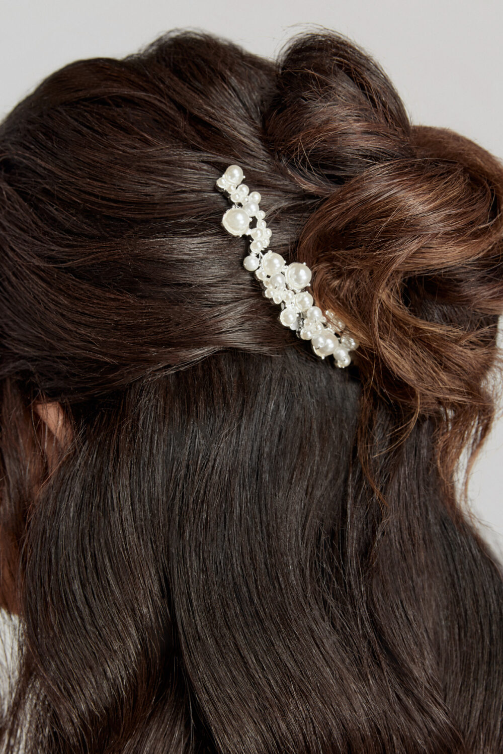 A pearl hair accessory is pinned into a brunette’s half-up hairstyle.