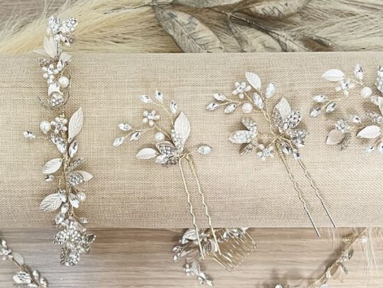 Several crystal and pearl bridal hairpins are arranged on a fabric roll.