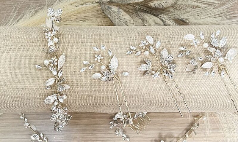 Several crystal and pearl bridal hairpins are arranged on a fabric roll.