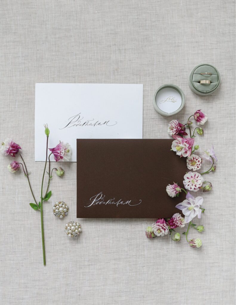 Flat-lay photo of wedding invitations arranged on a linen surface with delicate flowers and a ribbon.
