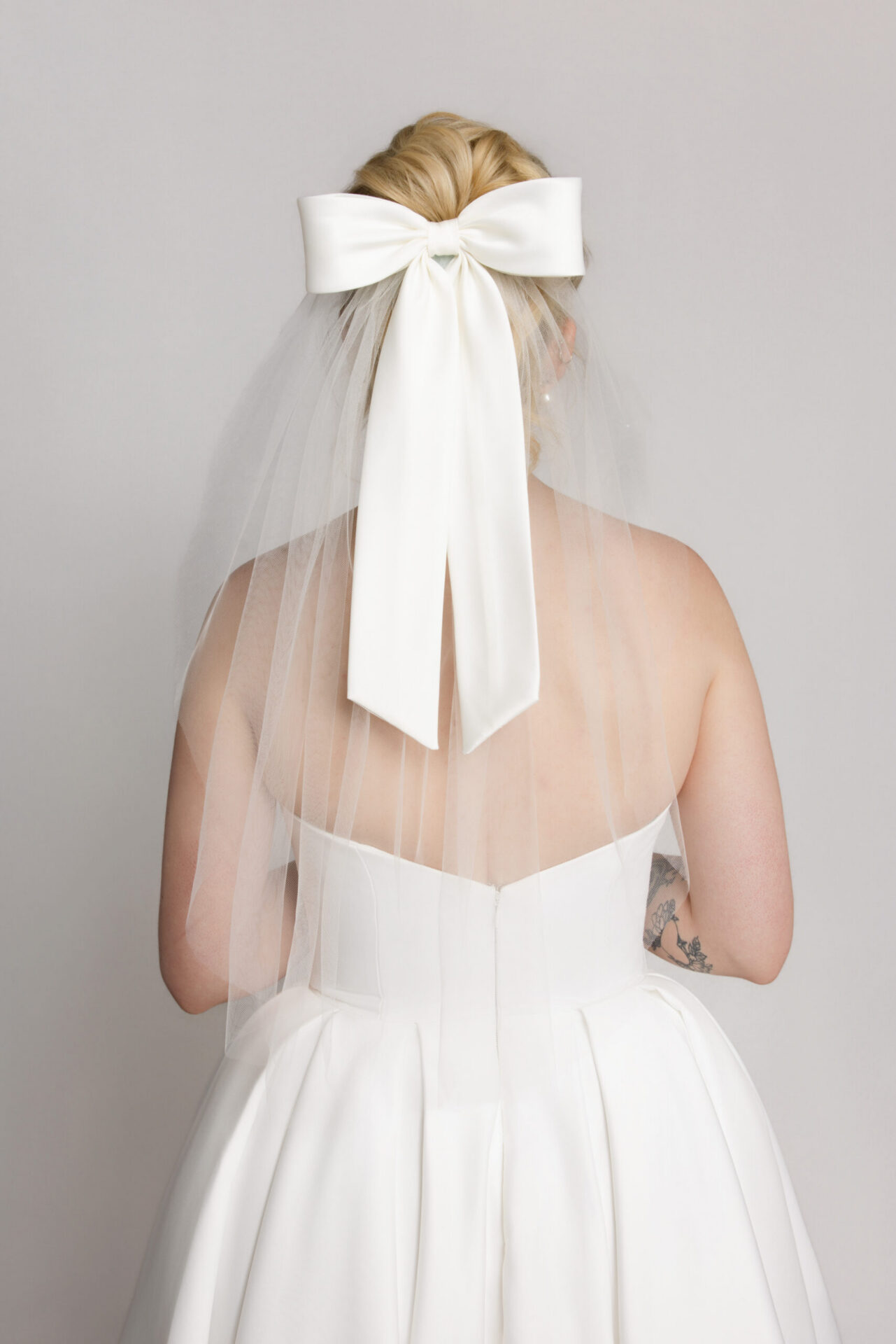 Back view of a bride with a large bow and veil attached to her hairstyle.