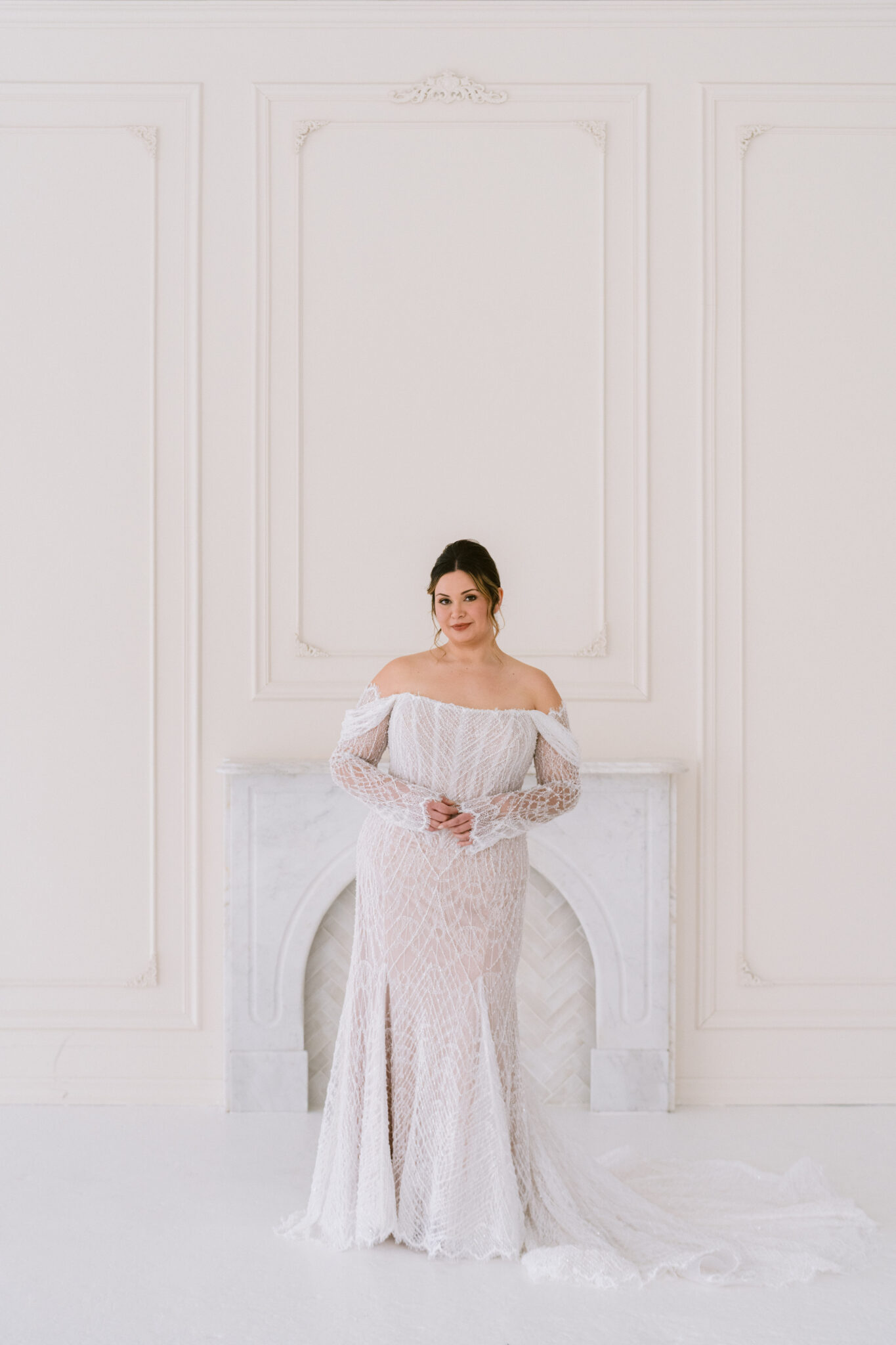 Front view of a curve off-shoulder wedding gown with fitted silhouette and soft train.